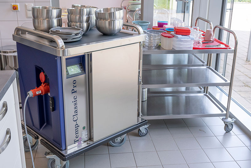Das Bild zeigt den Temp-Classic Pro mit Thermo Schüsseln in der Küche der Kita Regenbogenland, der DRK Delmenhorst, über deren Praxis im Bericht 'DRK Delmenhorst: Best Practice Beispiel' auf der JUNIOR-SERVE Website berichtet wird.